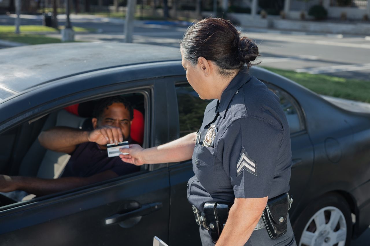 Police officer checking a driver's license during a traffic stop for a California VC 14601.1(a) suspended license violation.