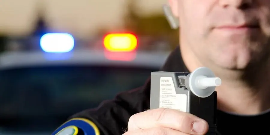 Police officer holding a breathalyzer device during a DUI traffic stop that could cost a California professional license